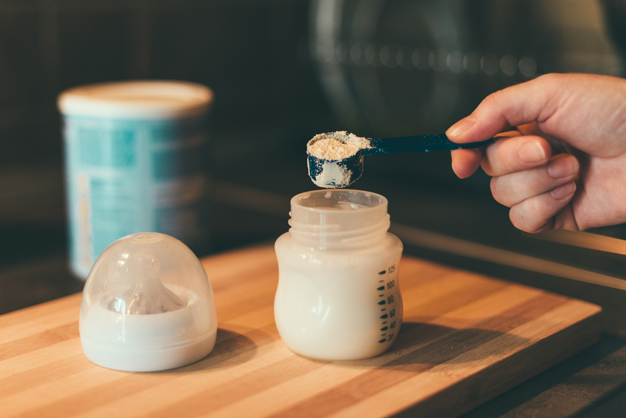 parent scooping baby formula into bottle