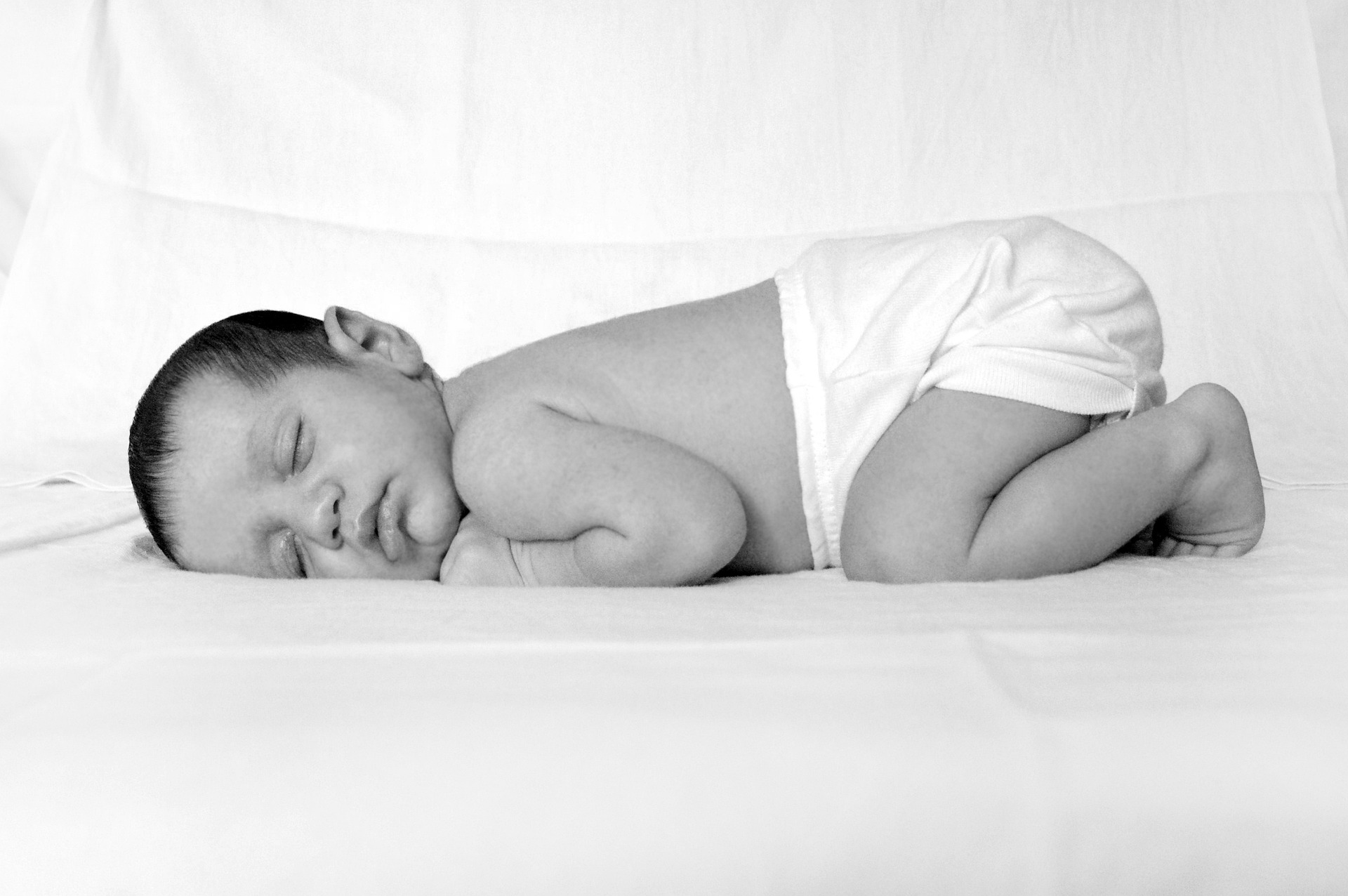 baby sleeping on their stomach with a diaper on