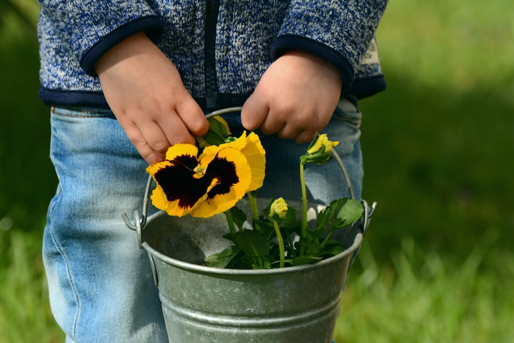 child holding a pot of flowers