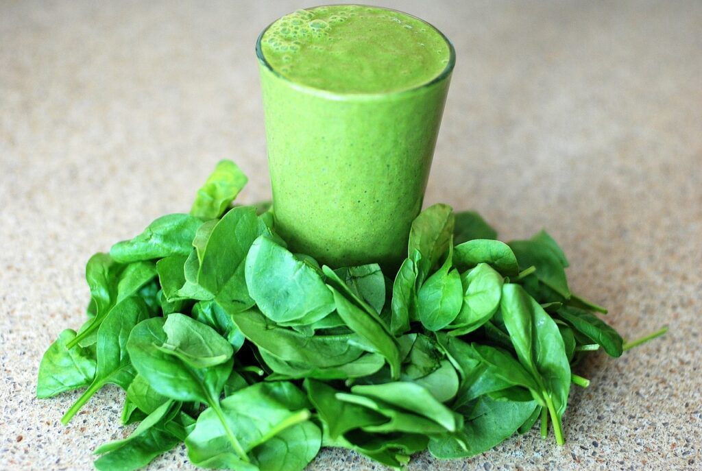 leaves of spinach around a spinach smoothie