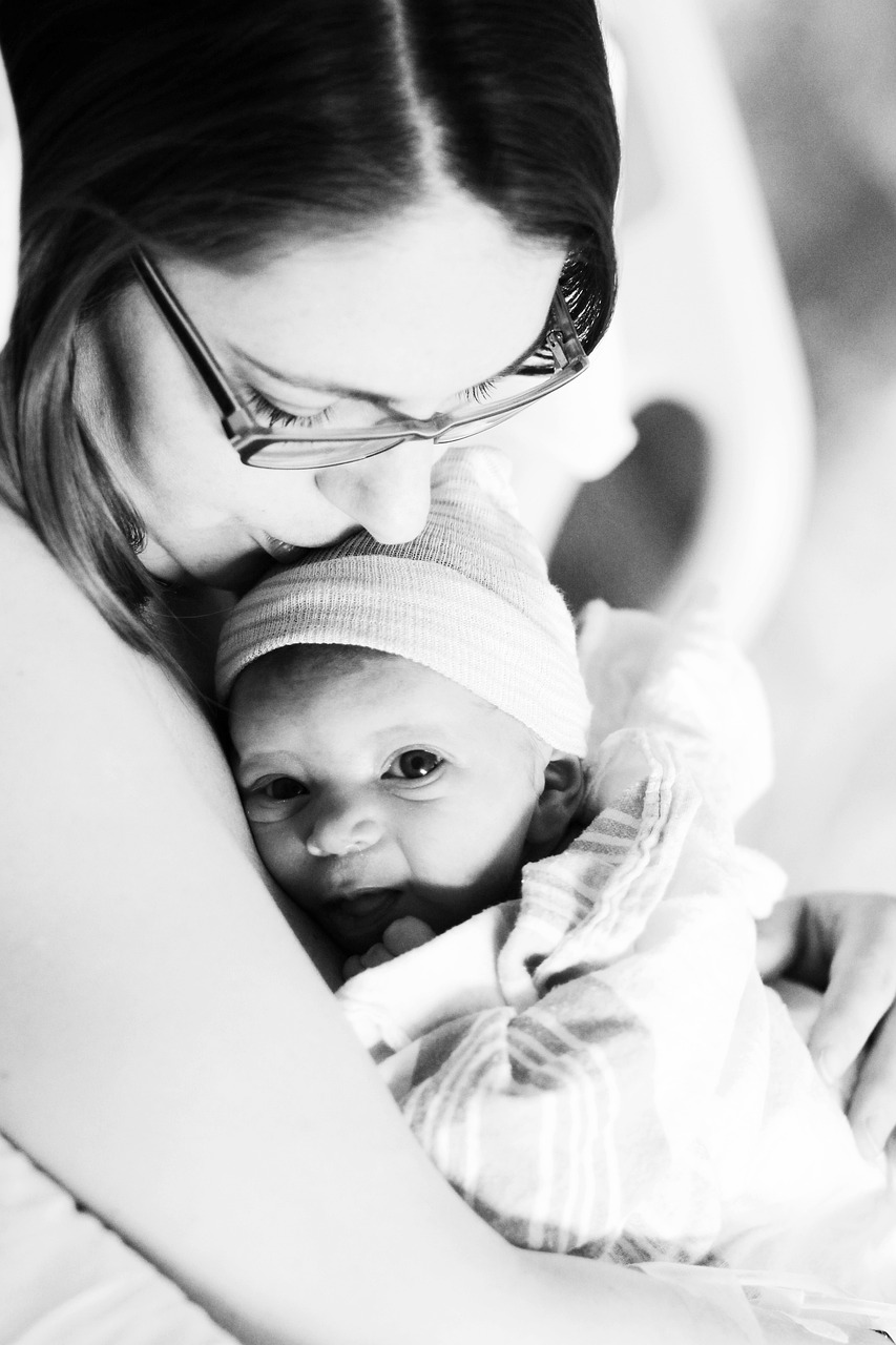 mother holding baby and kissing her head