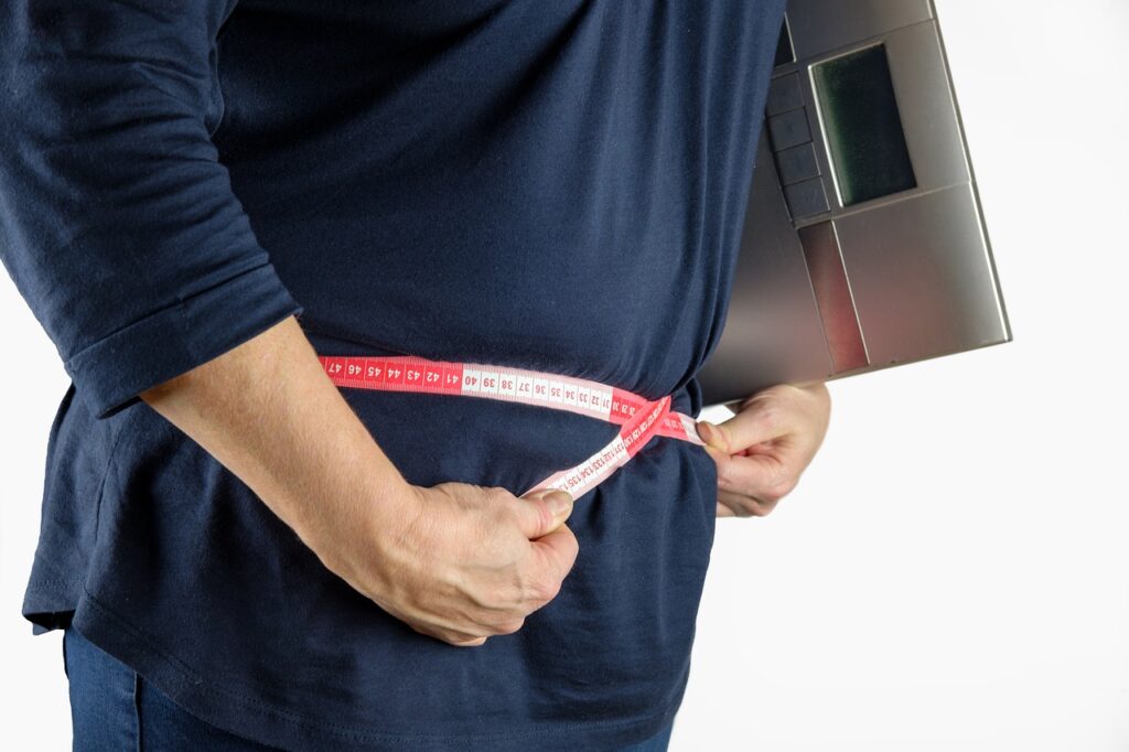 overweight person measuring their waist